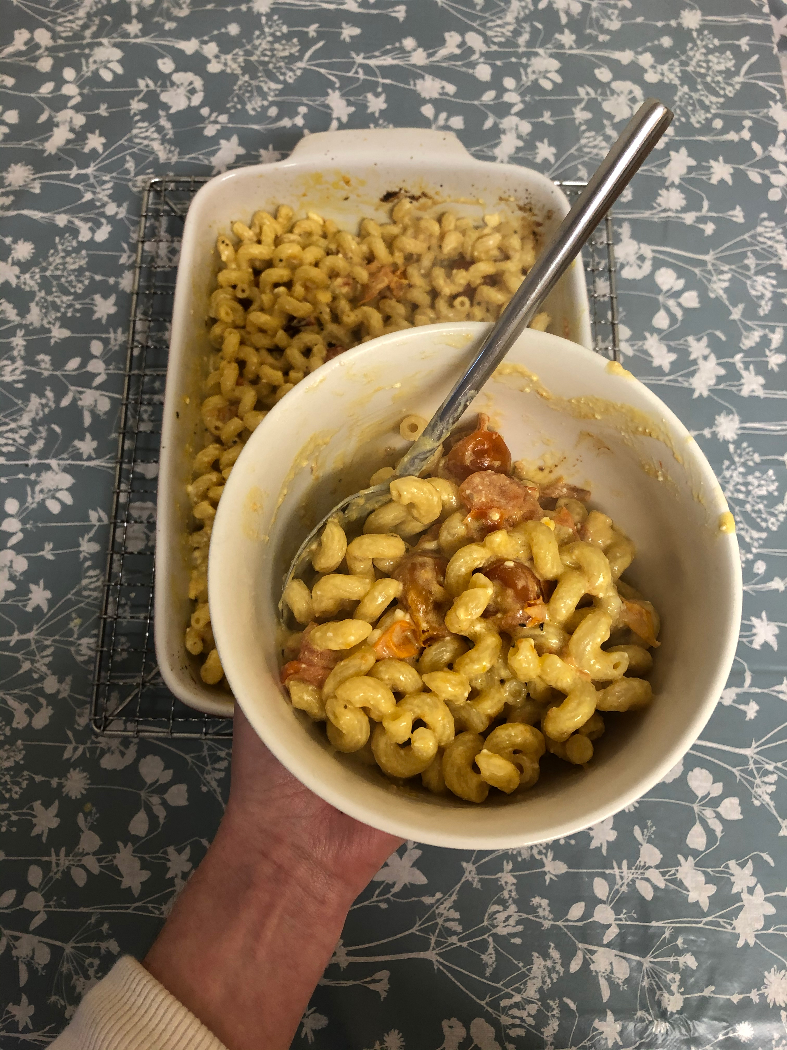 Editor holding the finished feta and tomato spirali in a bowl with the pasta combined with the sauce